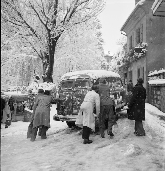 Snowfall in Lausanne: men bump-starting a car; 1952.