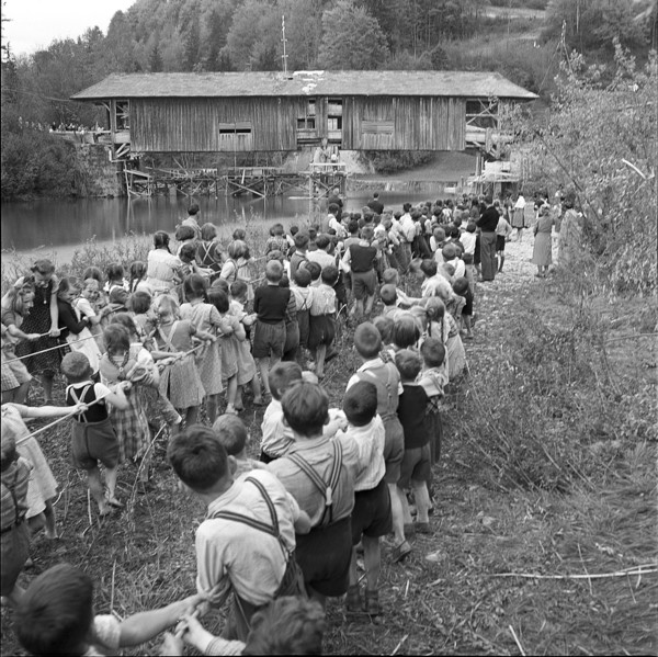 Children helping to displace an old wooden bridge; 1952.
