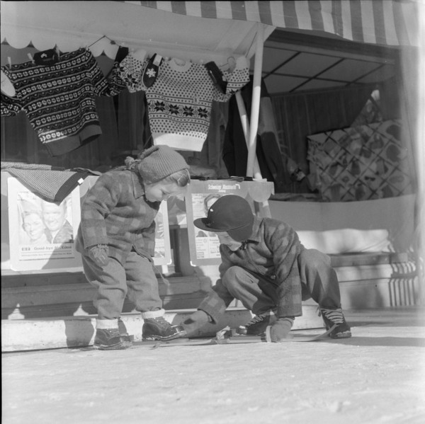 Steering; boy helping girl to put on her skis; 1957
