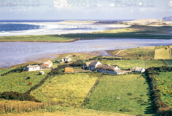 View over thatched farmhouse buildings to Magheraroarty Beach.