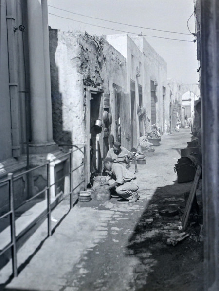 Workers with metal pots in narrow alleyway street in old town medina.