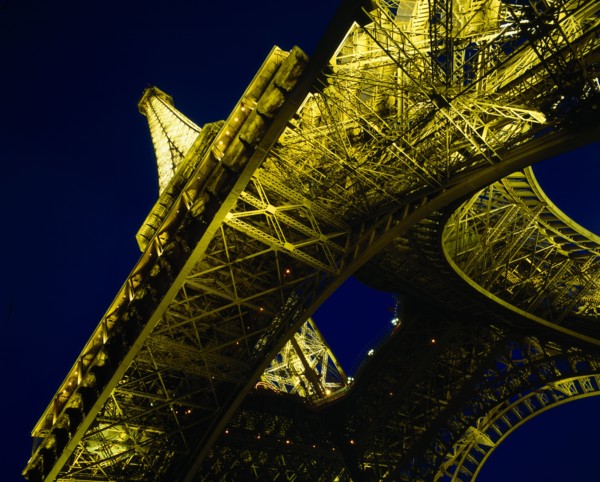 FRANCE, Ile de France, Paris, Eiffel Tower.  Angled view from below floodlit at night.