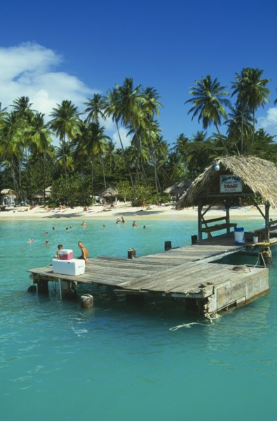 WEST INDIES, Tobago, Pigeon Point, Boat jetty with tourist sitting down and the beach behind with