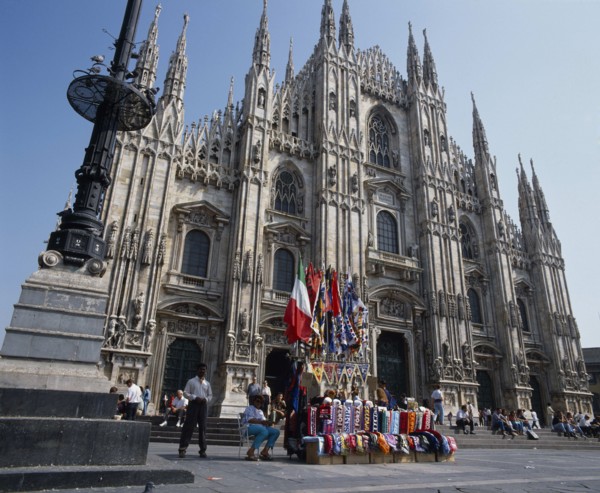 ITALY, Lombardy, Milan, Cathedral frontage with tourists  beside a souvenir stall selling flags and