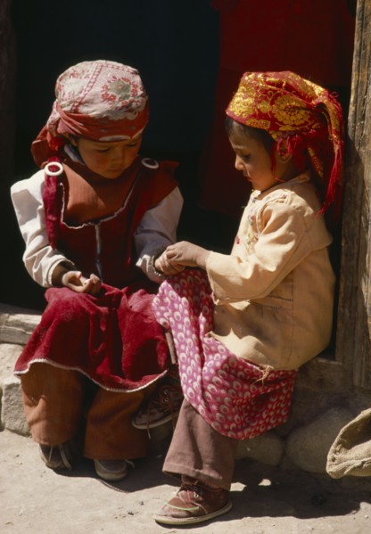CHINA, Xinjiang Province, Children, Two Tadjik girls sitting on step beside wooden door frame.