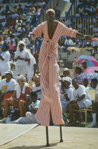 WEST INDIES, Barbados, Crop Over, Stiltman in pink and white at traditional harvest festival to