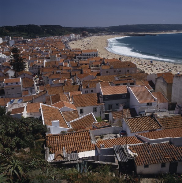 PORTUGAL, Estremadura, Nazara, View over main beach and town roof tops with mountains behind