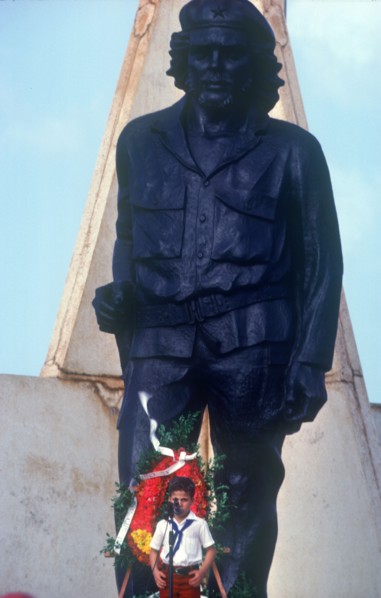 CUBA, Holguin Province, Moa, Young child at memorial day with statue of Che Guevara behind.