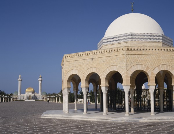 TUNISIA, Monastir, Bourguiba Mausoleum in distance beyond an arched portico with a white dome