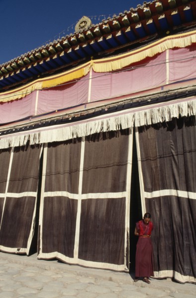 CHINA, Quinghai, Tongren, Monk standing at the entrance to a Tibetan monastery