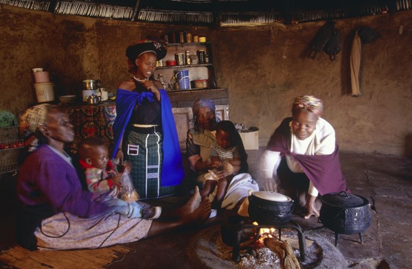 SOUTH AFRICA, Kwa Zulu Natal , Msinga, Zulu women and children cooking inside a Zulu hut or indlu.