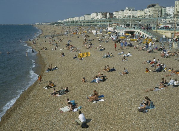 ENGLAND, East Sussex, Brighton, People sitting on the beach in summertime