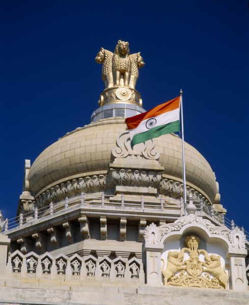 INDIA, Karnataka, Bangalore, "Vidhana Soudha building.  Exterior detail of roof dome, crest, flag