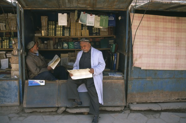 CHINA, Xinjiang , Kashgar, Muslim men reading at bookstall.
