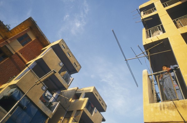 INDIA, Uttar Pradesh , Delhi, New housing estate. View looking up at buildings with boy standing on