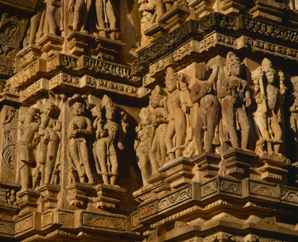 INDIA, Madhya Pradesh, Khajuraho, Vishvanath Temple.  Detail of ornate carved figures around side.