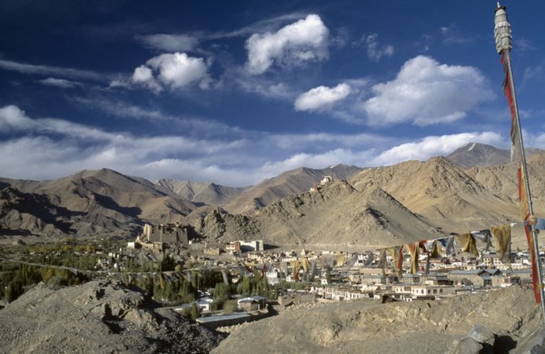 INDIA, Ladakh, Leh Valley , Prayer flags hanging above village set in mountainous landscape with