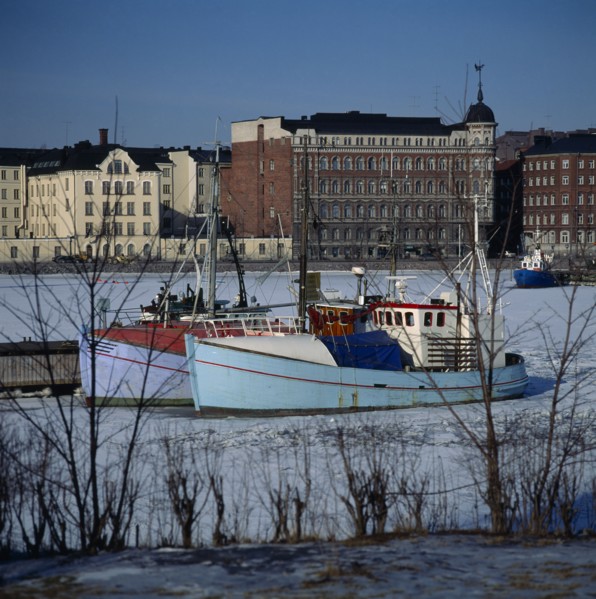 FINLAND, Uusimaa, Helsinki, "North Harbour,fishing boats,frozen sea,buildings beyond "