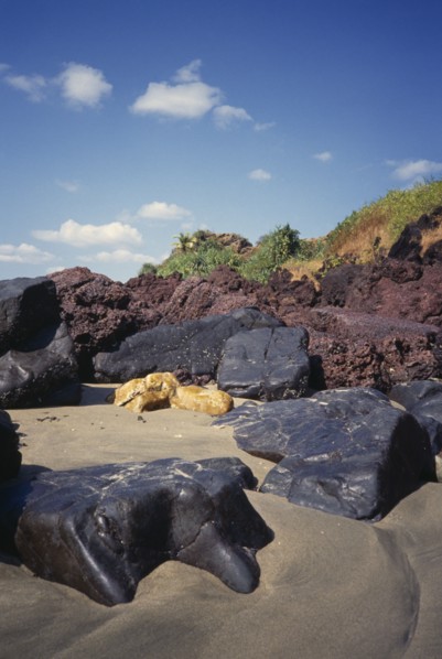 INDIA, Goa, Keri Beach, "Coastal landscape.  Large black, yellow and red rocks in the sand"
