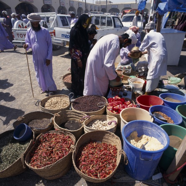 OMAN, Sharqiya, Sanaw, Local people in souk spice stall with spices in baskets and in bins.