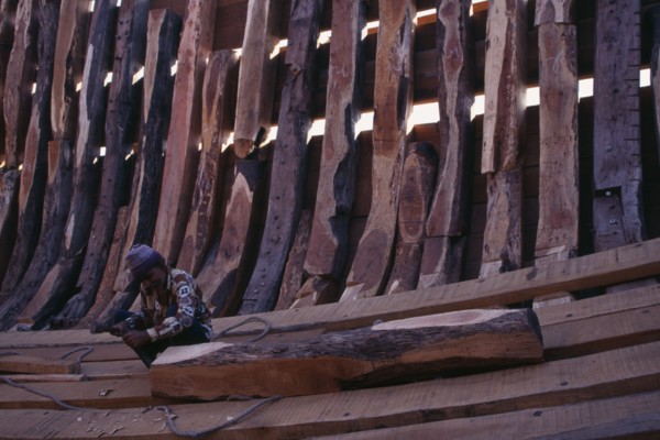 INDIA, Gujarat, Veraval, Shipbuilding.  Man working on interior shell of boat.