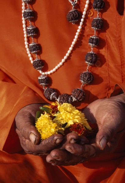 INDIA, Maharashtra, Nasik, Cropped shot of figure in orange robes and wearing prayer beads.  Close