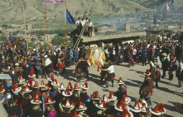 CHINA, Quinghai, Tongren, Tibetan festival with people wearing red tassled hats