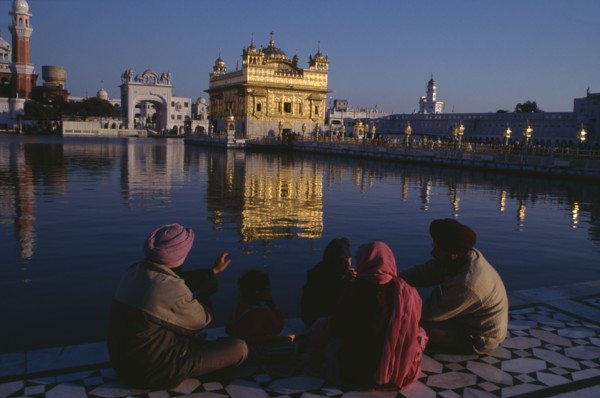 INDIA, Punjab, Amritsar, Golden Temple.  General view with pilgrim group sitting beside sacred pool
