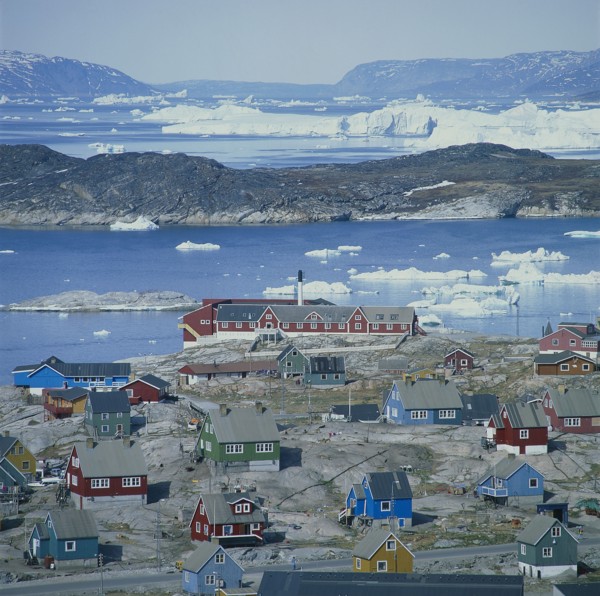 GREENLAND, Denmark, Jakobshaven, View over Ilulissat town with the sea and icebergs beyond coloured