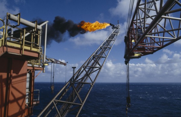 INDUSTRY, Factory, Oil Rig, Burning Off Gas. View along long pipe structure jutting out over the
