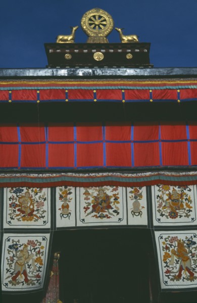 TIBET, Lhasa, Jokhang Temple, Golden Wheel of Dharma on roof of building covered in hanging fabrics