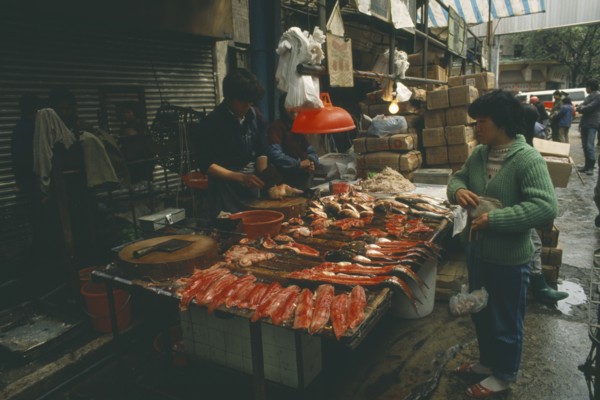 CHINA, Guangdong, Guangzhou, Fish stall in the market with vendor and customer.