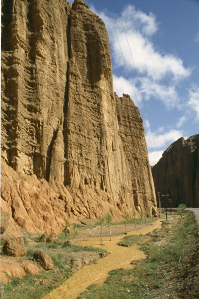 CHINA, Yellow River , Muddy water flowing alongside cliff edge and road