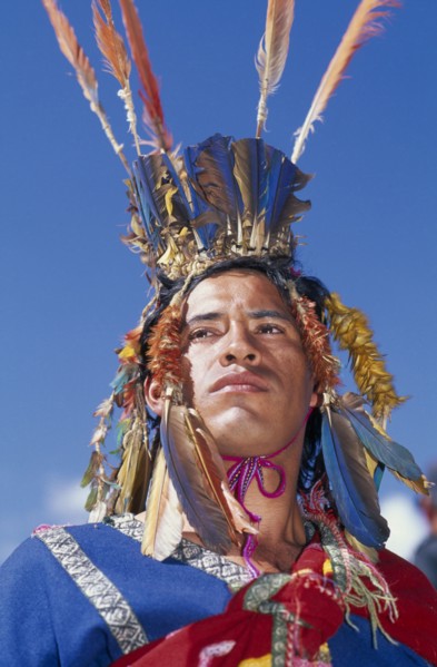 PERU, Cusco, Male figure in traditional costume and feathered headress at Inti Raymi.  Head and