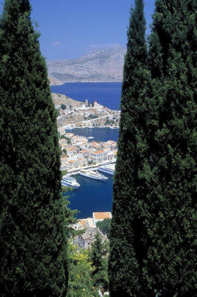 GREECE, Dodecanese, Symi, Gialo.  The town and harbour partly viewed between trees in the