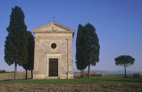ITALY, Tuscany, San Querico, "Small stone chapel, facade with cypress trees growing beside it in an