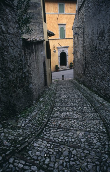 ITALY, Umbria, Spoleto, A narrow cobbled street leading down towards a yellow painted building