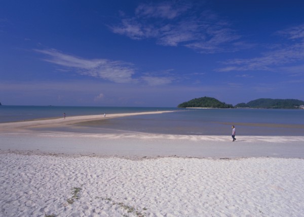 MALAYSIA, Langkawi, Kedah, Pantai Cenang beach with man walking near the the sand bar at low tide