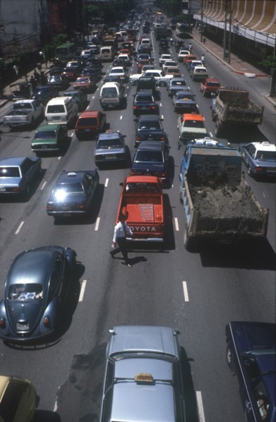 THAILAND, Bangkok, Pedestrian crossing road of six lanes of congested traffic.