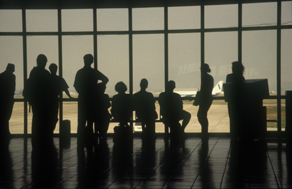 VIETNAM, Hanoi, People at the airport terminal viewed from behind silhouetted against the window.