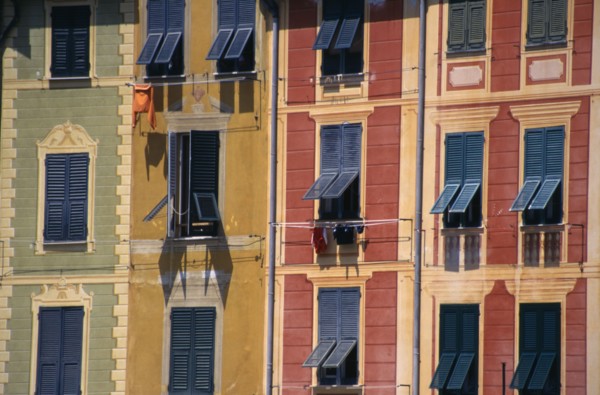 ITALY, Liguria, Portofino, Green yellow and red painted buildings with blue shutters by the harbour