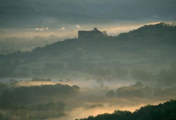 FRANCE, Aquitaine, Dordogne, "Castelnau-Bretenoux Castle silhouetted on hillside against pale,