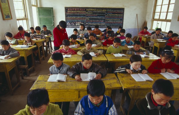 CHINA, Shaanxi Province, Xian, Classroom with school children reading at their desks with a teacher