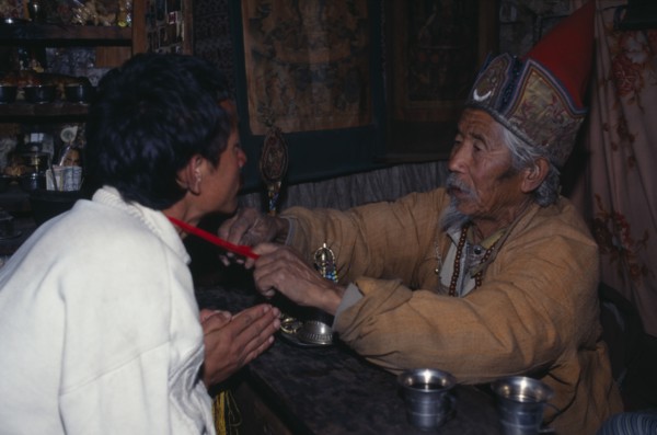 NEPAL, Annapurna Region, Manang, Lama blessing good luck thread for safe journey.  Also known as