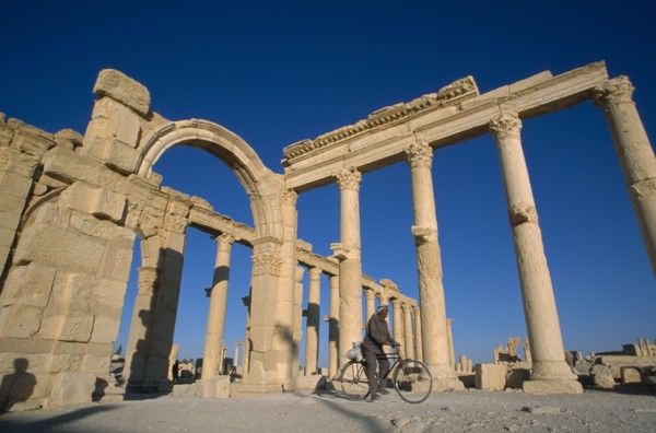SYRIA, Central, Tadmur, Colonnade and archway with man on a bicycle framed between columns.
