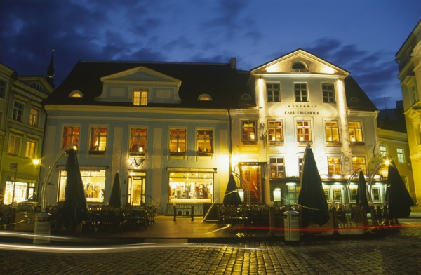 ESTONIA, Tallinn, Raekoja Plats.  Exterior of cafe and restaurant and clothes shop illuminated at