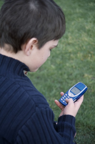 COMMUNICATIONS, Telephones, Mobile, View over the shoulder of a boy holding a blue mobile phone