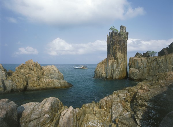 THAILAND, Trat Province, Koh Chang, Laem Chai Chet. Coastal rock formations and cliffs with a small