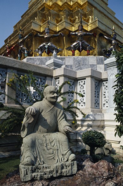 THAILAND, Bangkok, Grand Palace, Aka Wat Phra Kaeo. Stone statue on rockery next to small tree in