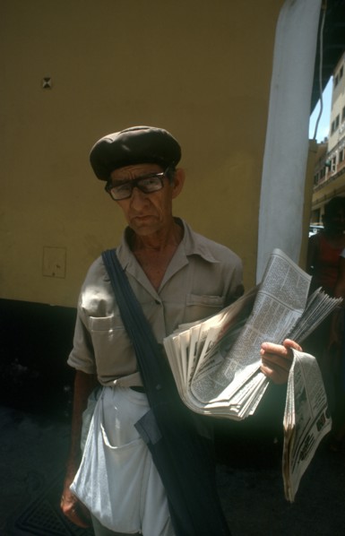 CUBA, Havana, Newspaper vendor standing in the street